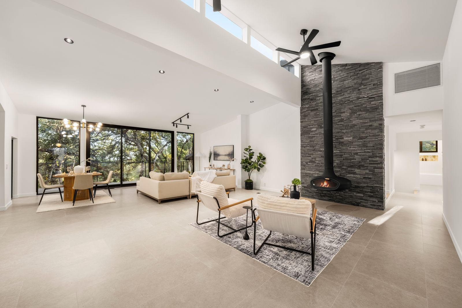Great room with floating fireplace, walls of glass, and treetop views
