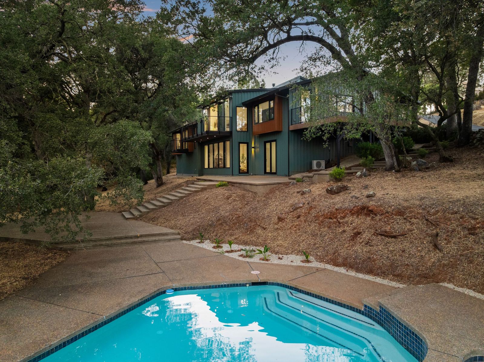 Rear elevation of the home with pool at dusk