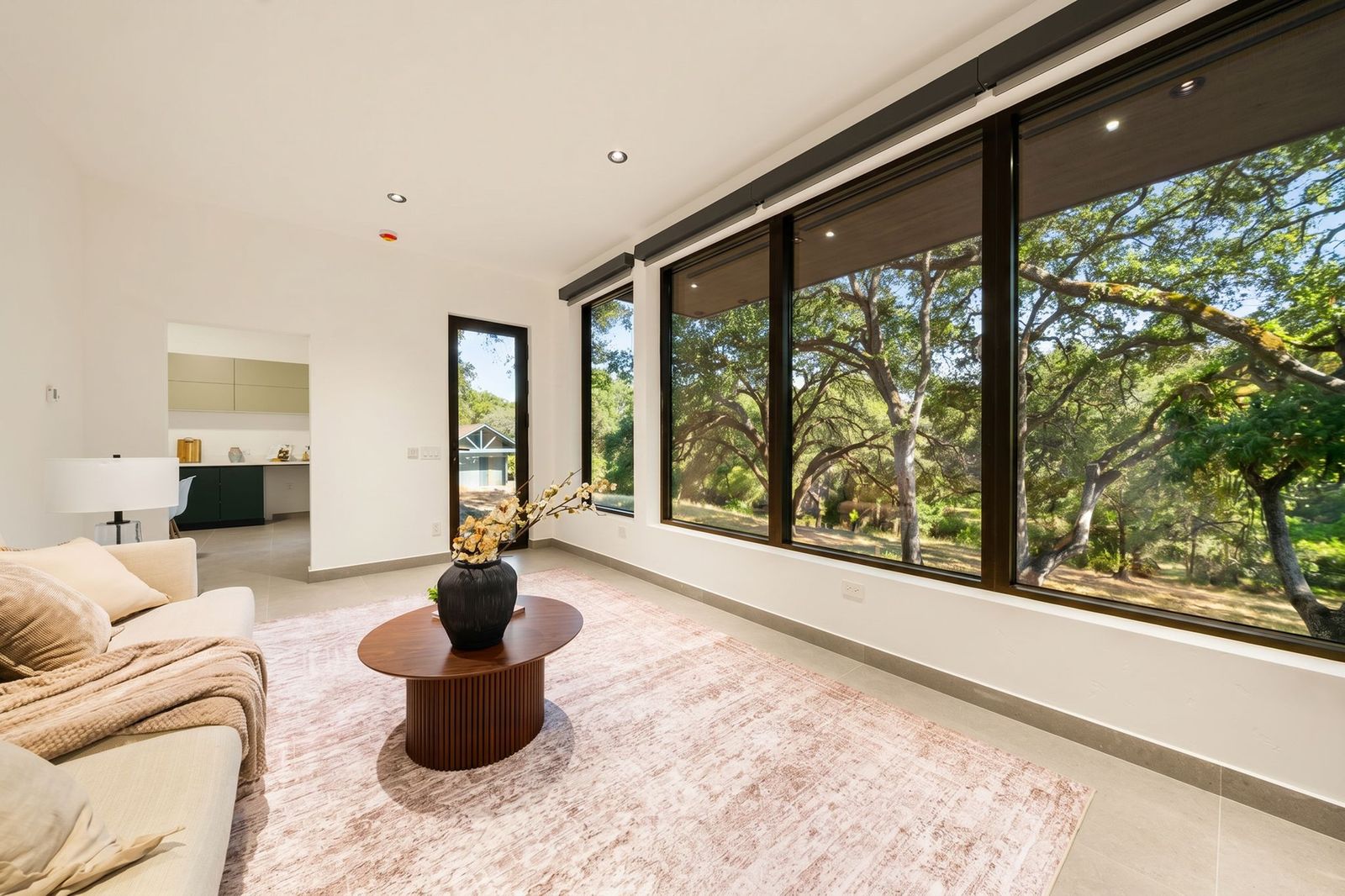 ADU living area and bedroom with walls of glass to the oaks